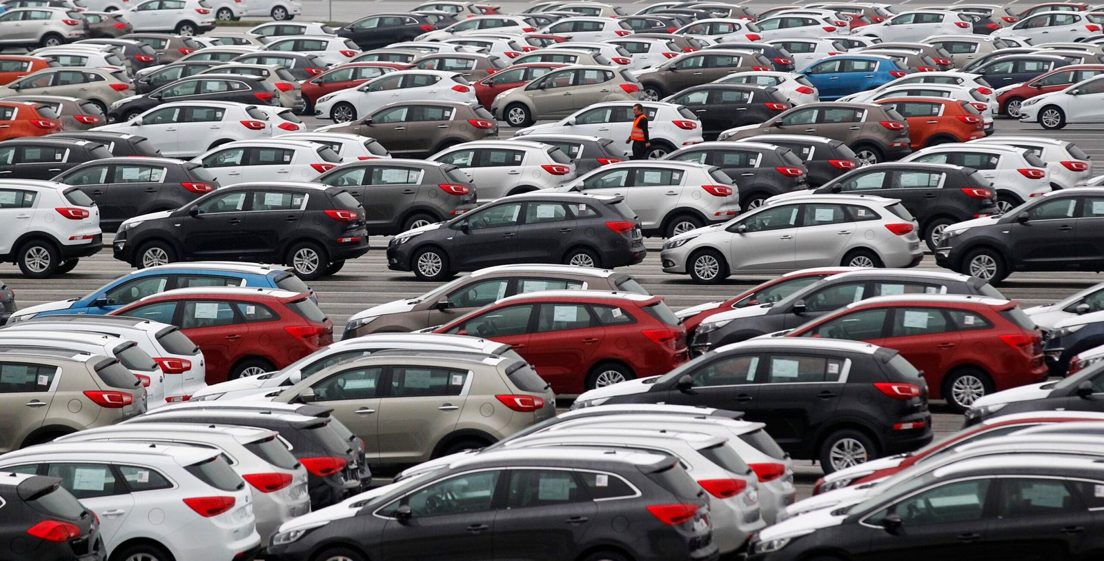 A worker walks through a parking lot of Kia cars ready for shipping, in its factory in Zilina, 200 kilometres north of Bratislava October 3, 2012. Carmakers that cut costs last decade in Western Europe like Volkswagen, or those who were never saddled with expensive factories there, such as Korea’s Hyundai and Kia, are now investing in new designs, conquering new markets and ramping up production. Between them, VW Group, Mercedes, Kia and Hyundai have raised their share of the European market to 35.5 percent in the eight months to end August 2012, from 30 percent in the same period of 2010. Up the road in the foothills of Slovakia’s Fatra mountains, the most modern factory owned by Korean carmaker Kia Motors looks set to beat its production goal of 285,000 SUVs, compact and family cars. Picture taken October 3, 2012. To match Insight AUTOS-CENTRALEUROPE/          REUTERS/Petr Josek (SLOVAKIA – Tags: TRANSPORT BUSINESS EMPLOYMENT)