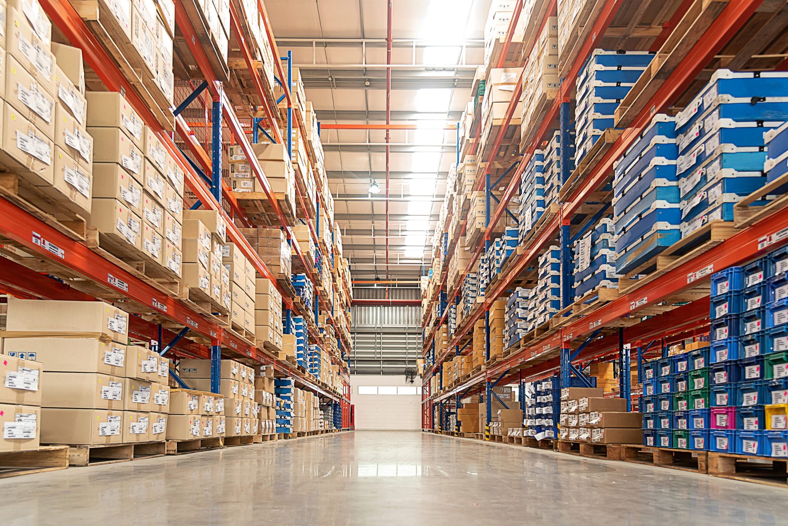 Rows of shelves with goods boxes in huge distribution warehouse at industrial storage factory.